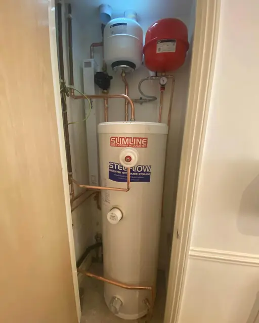 Unvented hot water cylinder installation with expansion vessels and copper pipework fitted in an airing cupboard.
